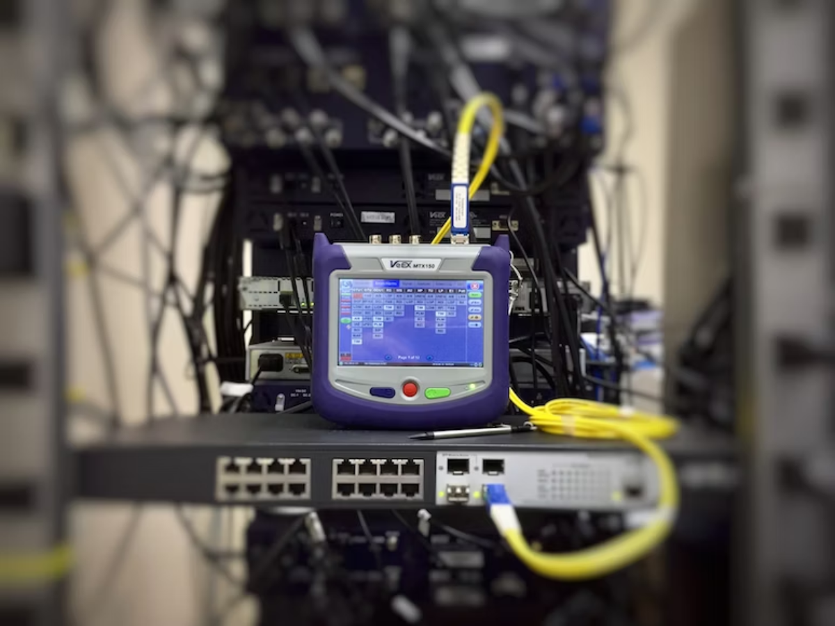 Vitex optical transceiver testing equipment with digital display showing CDR clock data recovery signal analysis connected to network switch with yellow fiber optic cables
