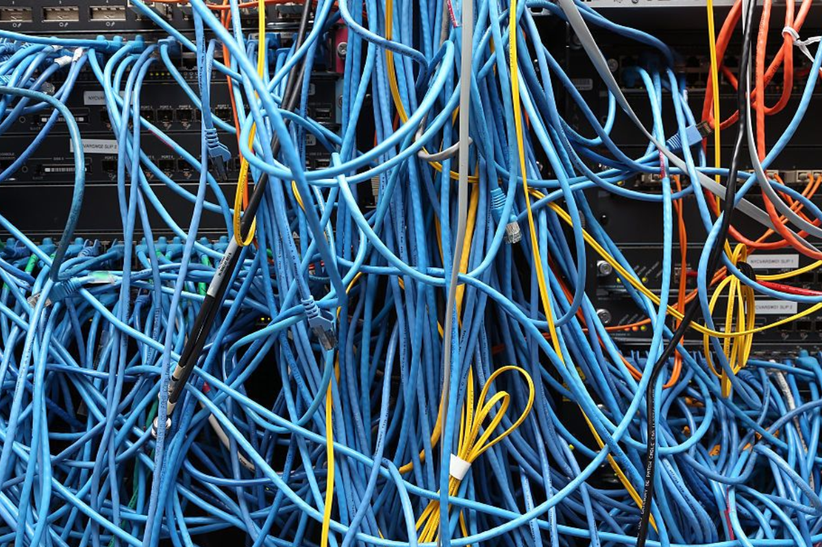 Network server rack with tangled blue ethernet cables and fiber optic connections illustrating data center infrastructure and energy consumption challenges